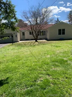 a front view of house with yard and trees in the background