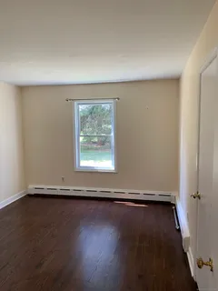 an empty room with wooden floor and window