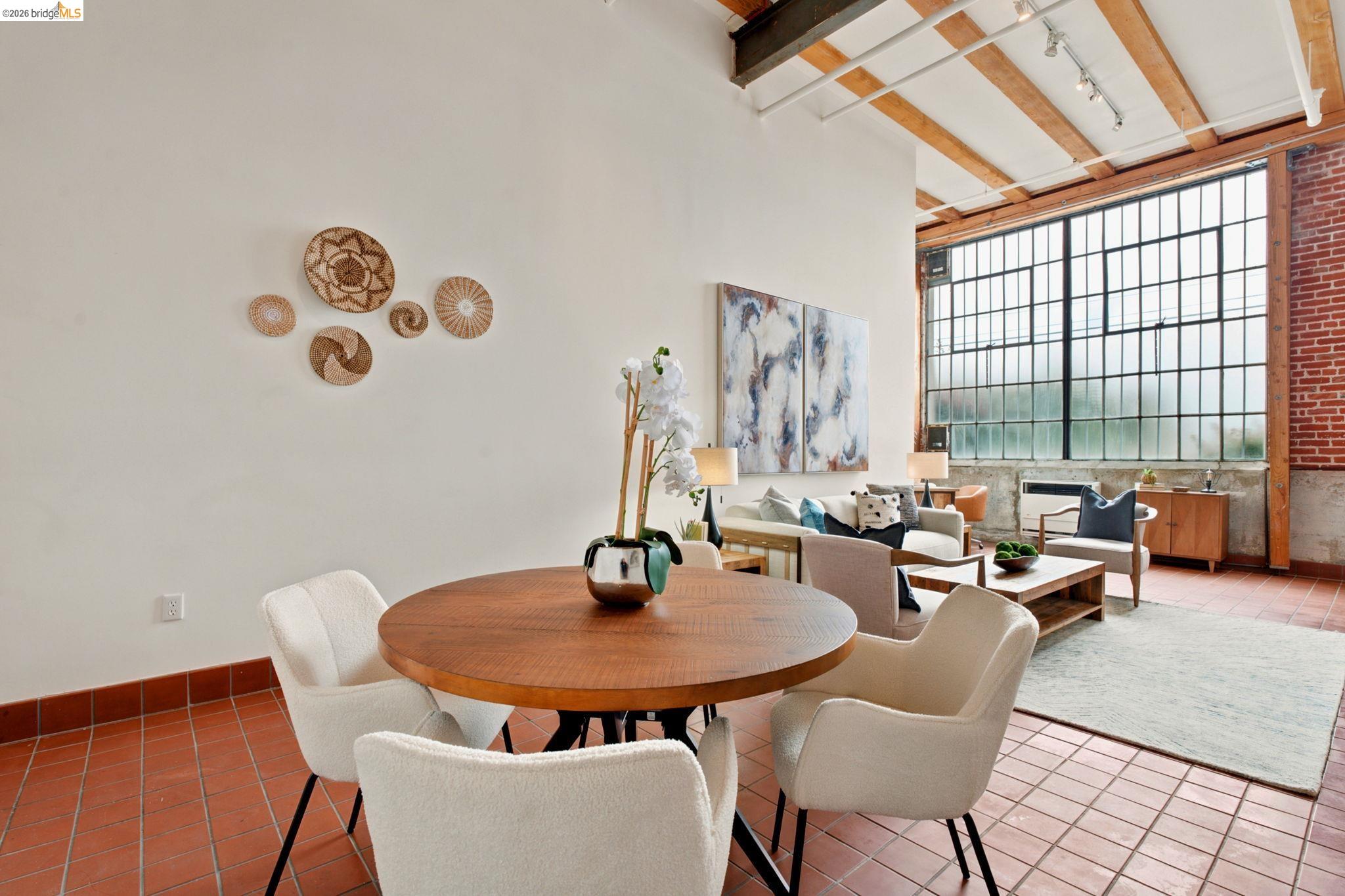 1920 Union Street, Unit 9 Oakland, CA 94607 - Photo 12 of 35 Open-concept living area featuring terracotta-style floor tiles, exposed brick accents, and a beamed ceiling