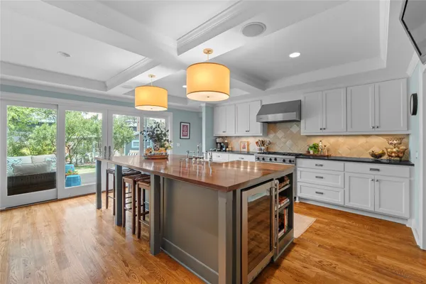 a kitchen with kitchen island granite countertop wooden floors and a view of living room