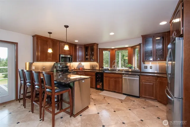 a kitchen with stainless steel appliances granite countertop a sink a stove a dining table and chairs