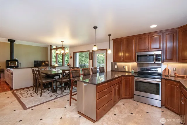 a kitchen with stainless steel appliances granite countertop a stove top oven a sink dishwasher a dining table and chairs with wooden floor