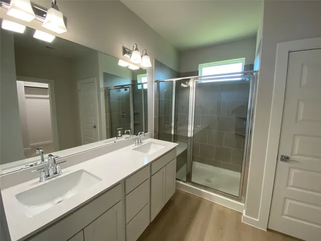 a bathroom with a double vanity sink mirror and shower