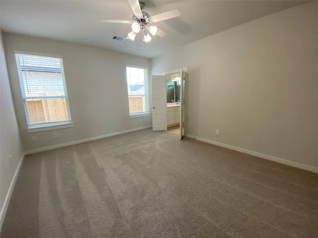 an empty room with windows and fan