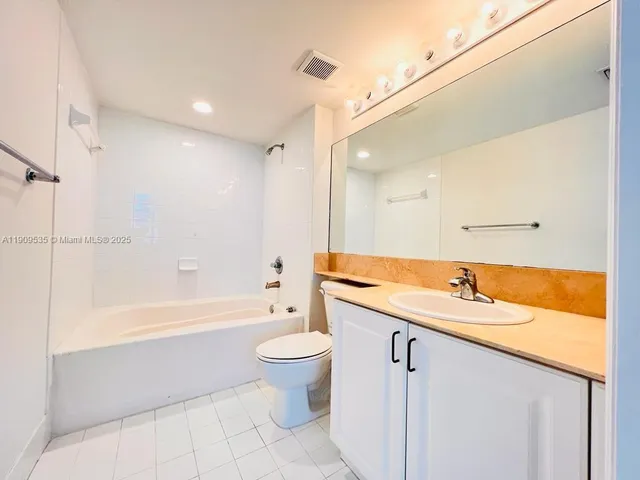 a bathroom with a granite countertop sink a toilet and bathtub