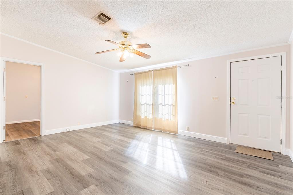 16314 Tiger Trail Spring Hill, FL 34610 - Photo 7 of 43 a view of an empty room with wooden floor and a window