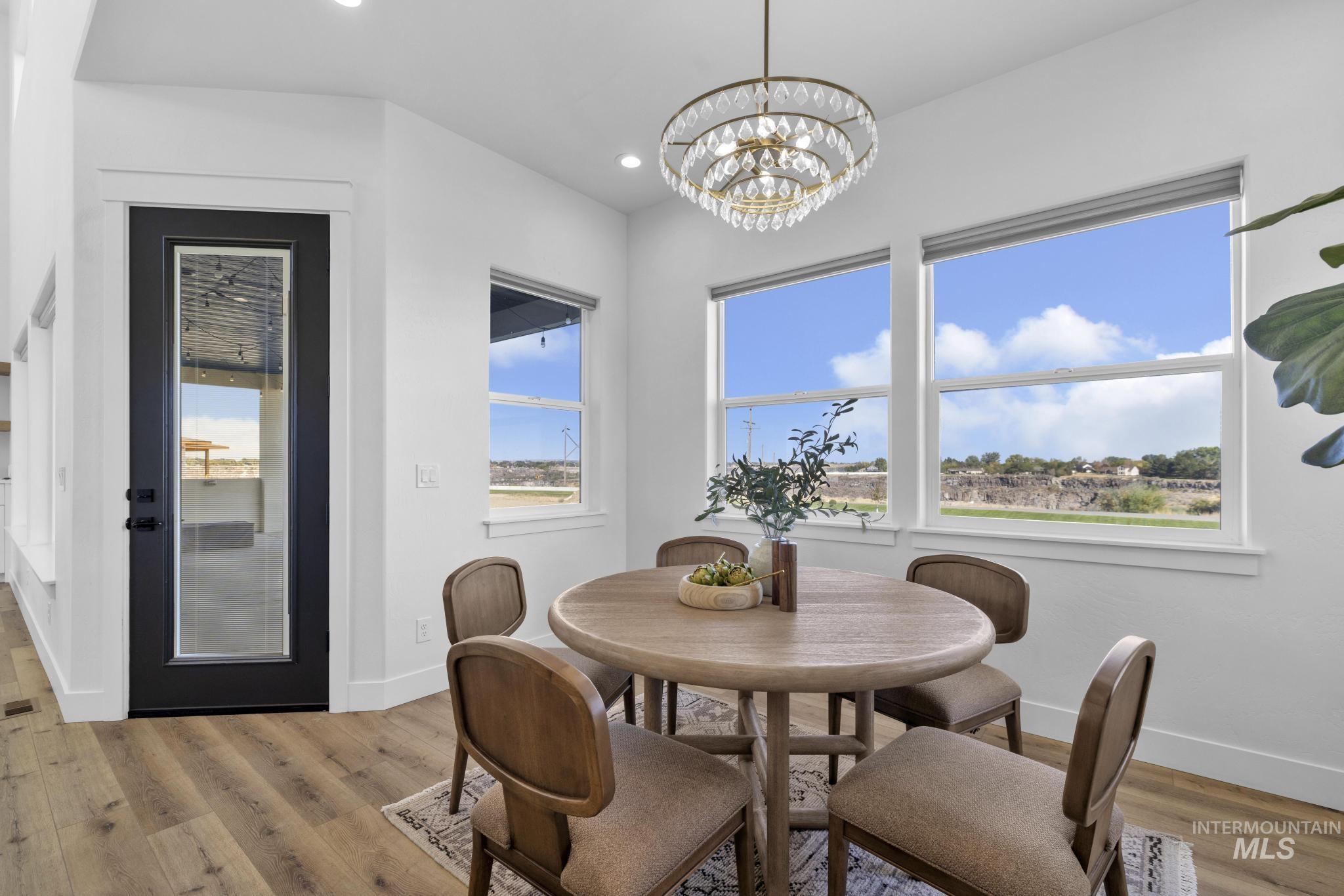 4280 Rim Vista Road Filer, ID 83328 - Photo 17 of 50 Wood-finish flooring, white walls, black-frame glass-panel door, multiple windows, and a crystal chandelier
