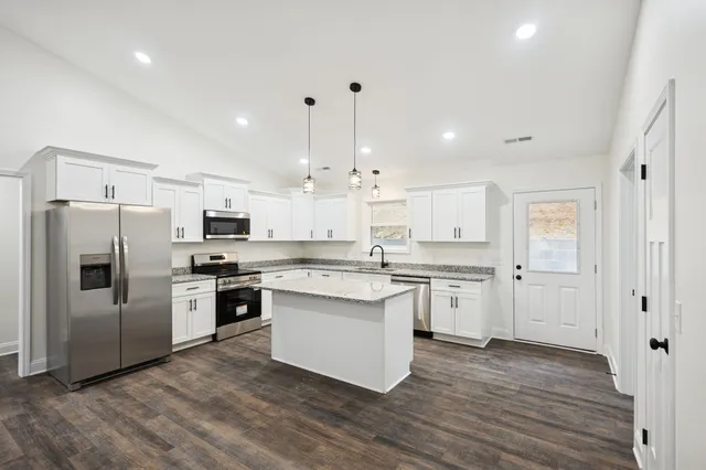a kitchen with kitchen island granite countertop a sink cabinets and stainless steel appliances