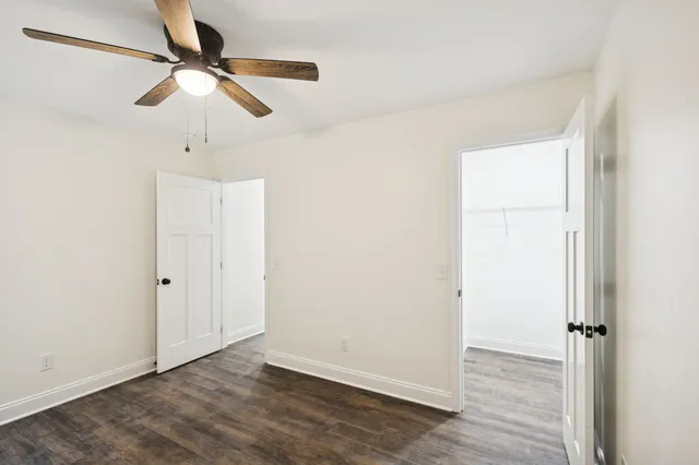 an empty room with wooden floor fan and windows