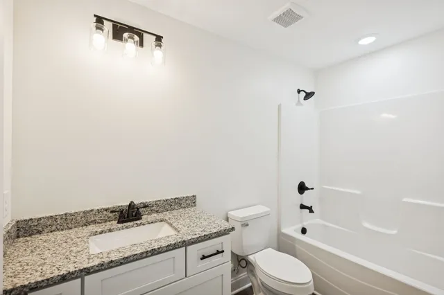 a bathroom with a granite countertop sink a toilet and shower