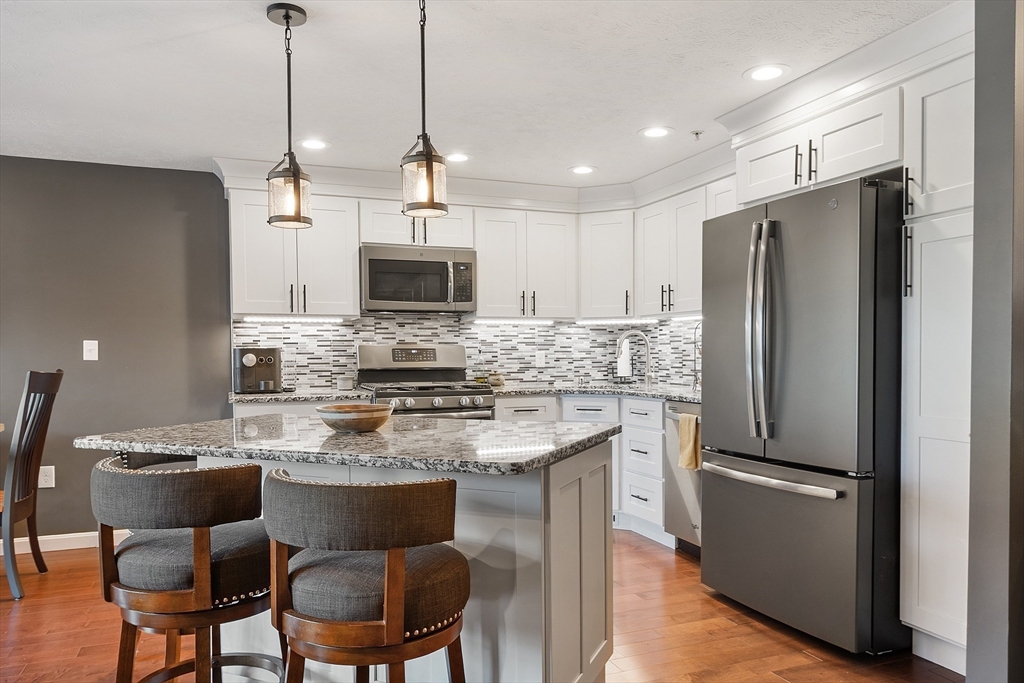 7 Green Briar Road, Unit 7 Fitchburg, MA 01420 - Photo 4 of 34 a kitchen with kitchen island a refrigerator a stove a microwave and island with wooden floor