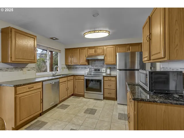 a kitchen with stainless steel appliances granite countertop a refrigerator a stove a sink and a microwave