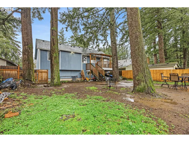 a view of a backyard with a table and chairs under an large trees