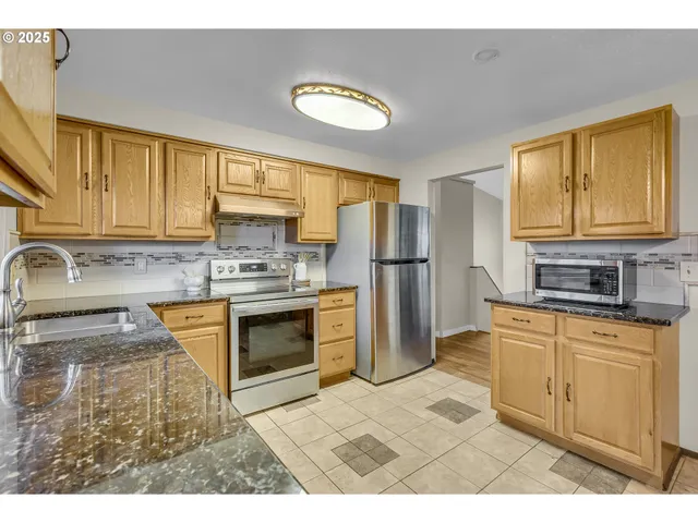 a kitchen with stainless steel appliances granite countertop a stove a sink and a microwave
