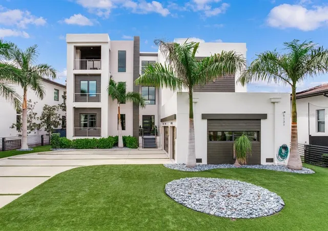 a view of a house with a yard and palm trees