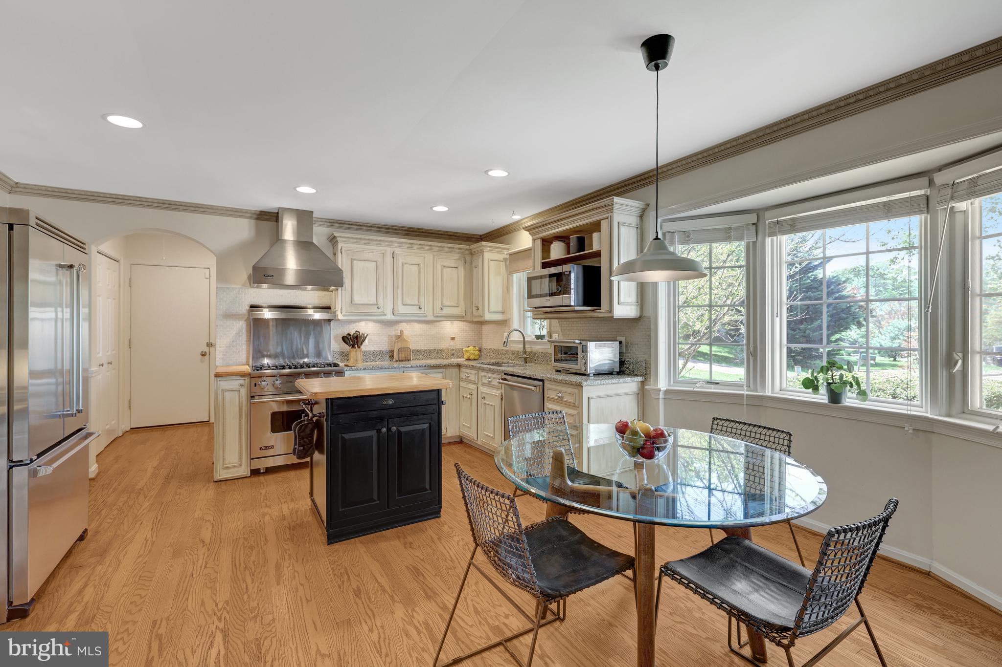 9001 Streamview Lane Vienna, VA 22182 - Photo 22 of 64 a kitchen with stainless steel appliances granite countertop a stove top oven a sink dishwasher a dining table and chairs with wooden floor