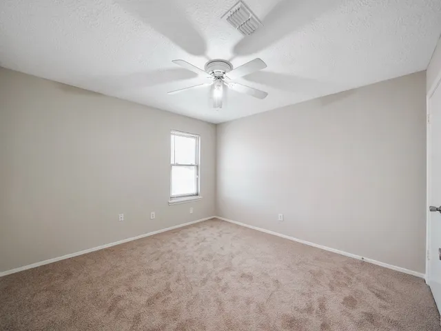 an empty room with windows and fan