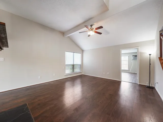 a view of an empty room with a window and wooden floor