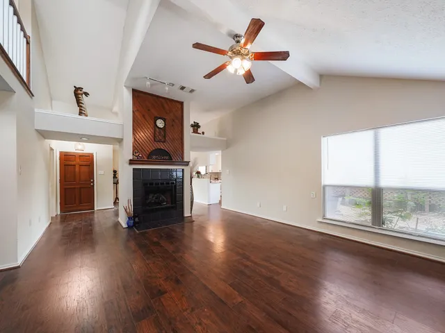 an empty room with wooden floor fireplace and windows