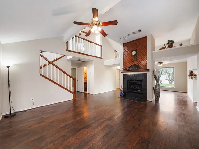 an empty room with wooden floor chandelier and fireplace