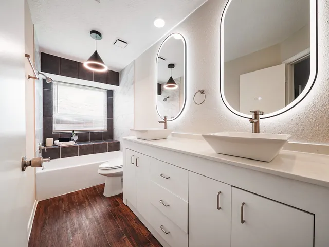 a bathroom with a double vanity sink toilet mirror and bathtub