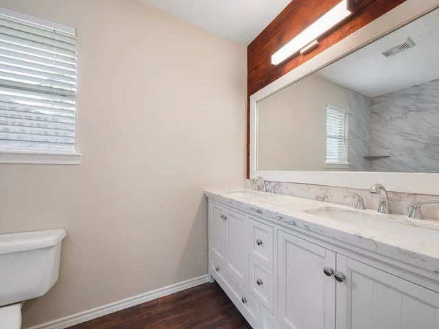 a bathroom with a granite countertop toilet a sink and a mirror