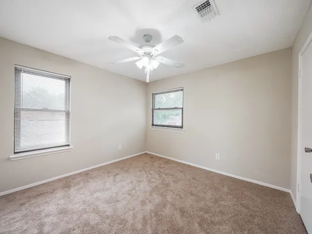 an empty room with windows and fan