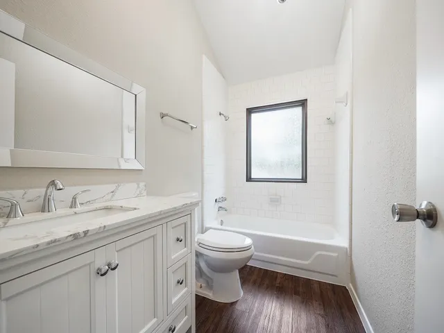 a bathroom with a granite countertop toilet a sink and a mirror
