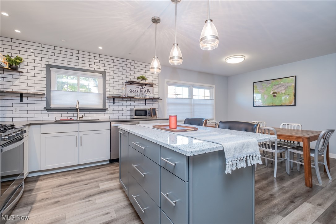 604 Everhard Road Southwest North Canton, OH 44709 - Photo 6 of 24 Kitchen with white cabinetry, light hardwood / wood-style floors, sink, and pendant lighting
