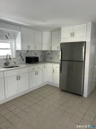 a kitchen with a sink a refrigerator and white cabinets