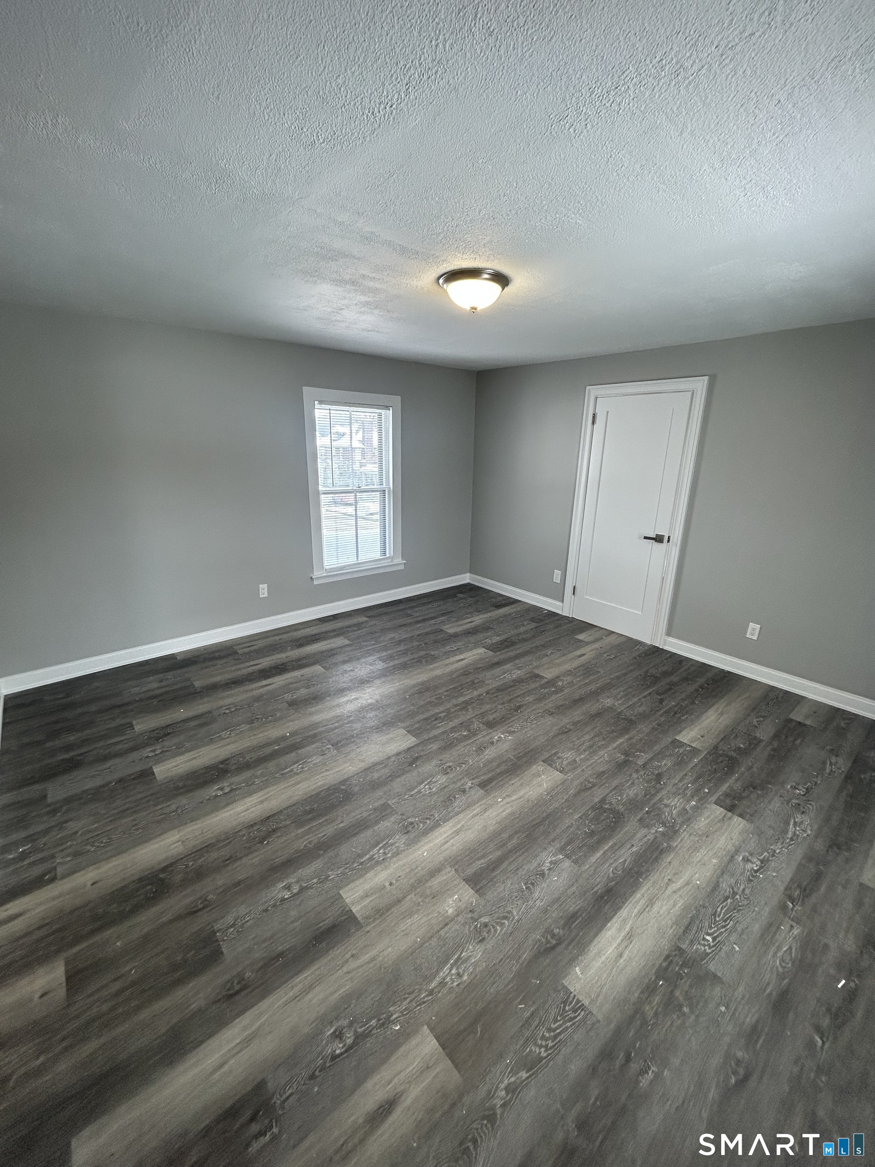 54 Forest Street, Unit 2 Torrington, CT 06790 - Photo 32 of 36 an empty room with wooden floor and windows