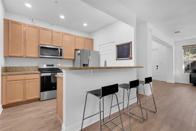 a kitchen with granite countertop a refrigerator stove top oven and sink