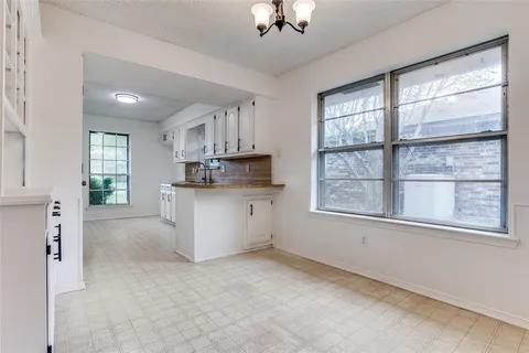 a large white kitchen with window and stainless steel appliances