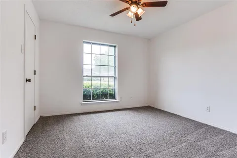 an empty room with a chandelier fan and windows