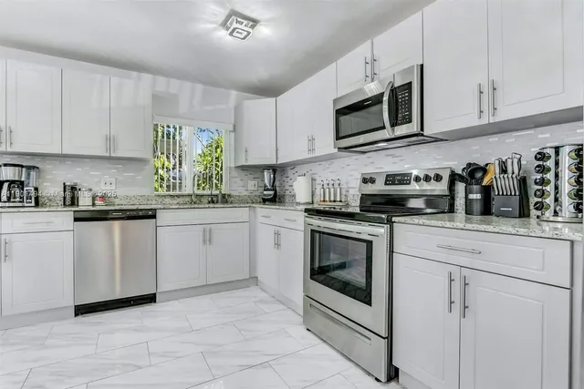 a kitchen with white cabinets stainless steel appliances and a sink
