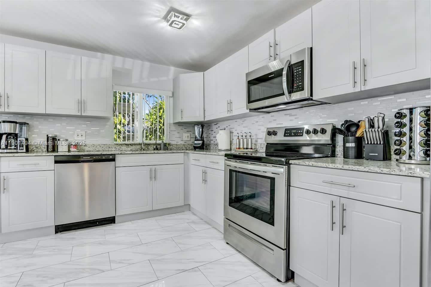 211 Southwest 4 Avenue Hallandale Beach, FL 33009 - Photo 5 of 25 a kitchen with white cabinets stainless steel appliances and a sink