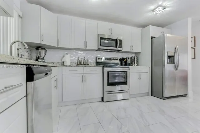 a kitchen with stainless steel appliances granite countertop a stove a sink and a refrigerator