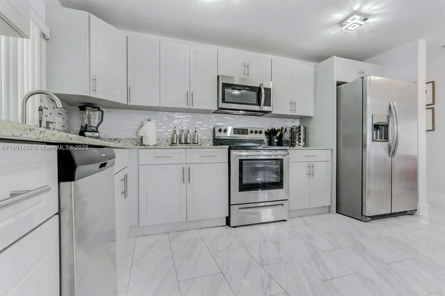 211 Southwest 4 Avenue Hallandale Beach, FL 33009 - Photo 6 of 25 a kitchen with stainless steel appliances granite countertop a stove a sink and a refrigerator