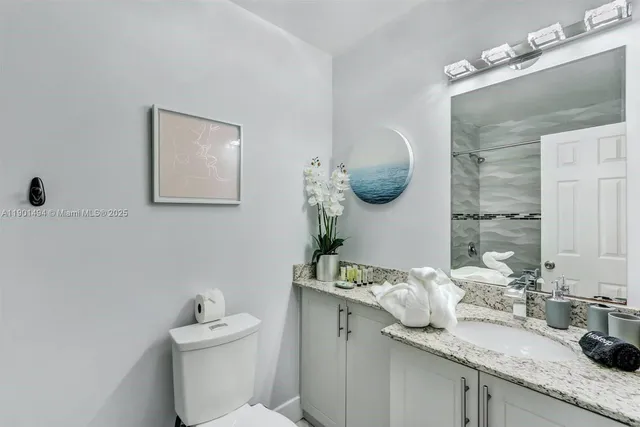 a bathroom with a granite countertop sink mirror and toilet
