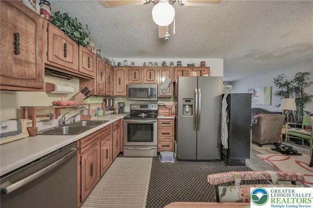 a kitchen with stainless steel appliances a sink a stove a chimney a dining table and chairs