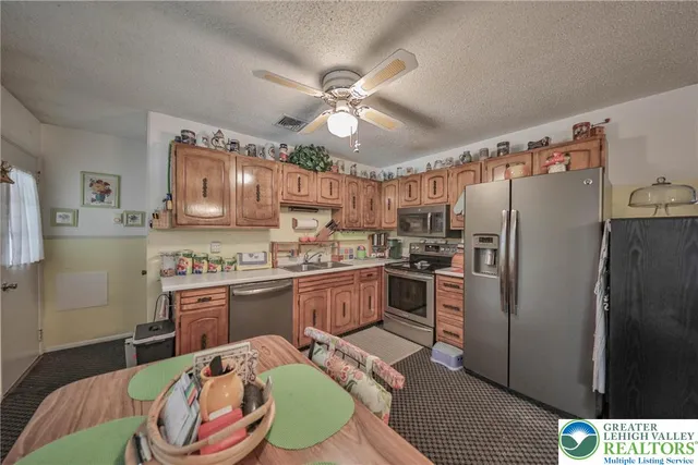 a open kitchen with stainless steel appliances kitchen island granite countertop a refrigerator a stove a microwave oven a sink with island and chairs