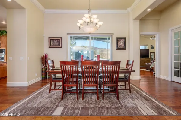 a kitchen with stainless steel appliances granite countertop a refrigerator a stove top oven a dining table and chairs with wooden floor