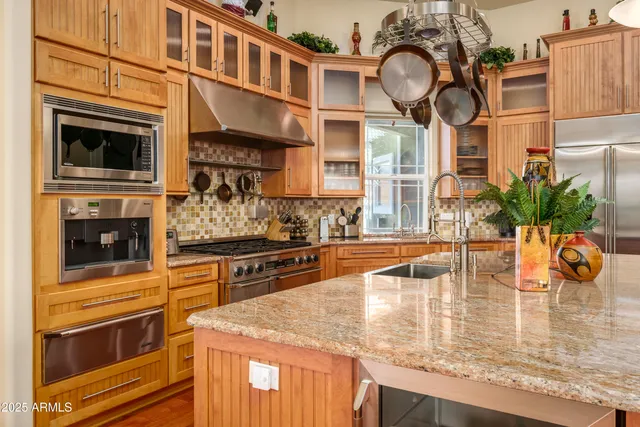 a kitchen with stainless steel appliances granite countertop a sink a stove and a wooden cabinets