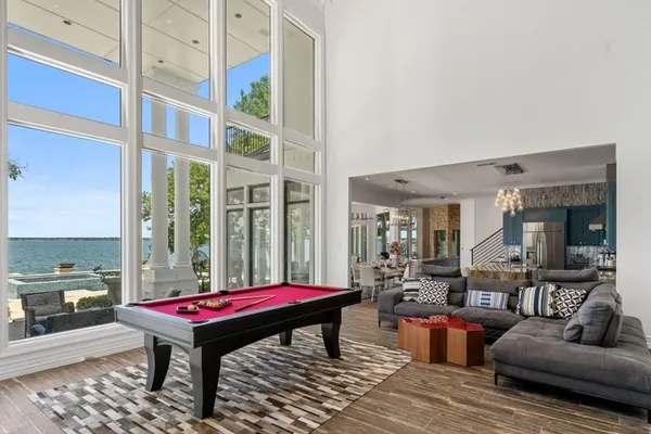a living room with furniture large windows and wooden floor