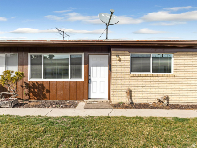 1478 North 75 West, Unit AD Sunset, UT 84015 - Photo 6 of 26 View of exterior entry featuring a yard, brick siding, and board and batten siding