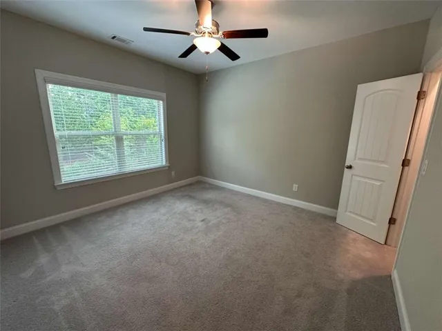 an empty room with a chandelier fan and windows