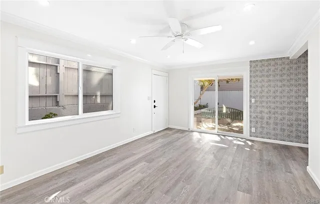 an empty room with wooden floor fan and windows