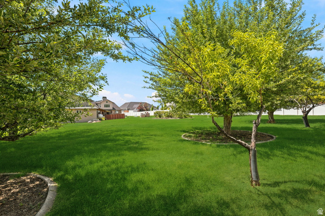 580 North 300 East Logan, UT 84321 - Photo 71 of 74 Expansive lawn area featuring mature trees with mulched bases and a perimeter fence