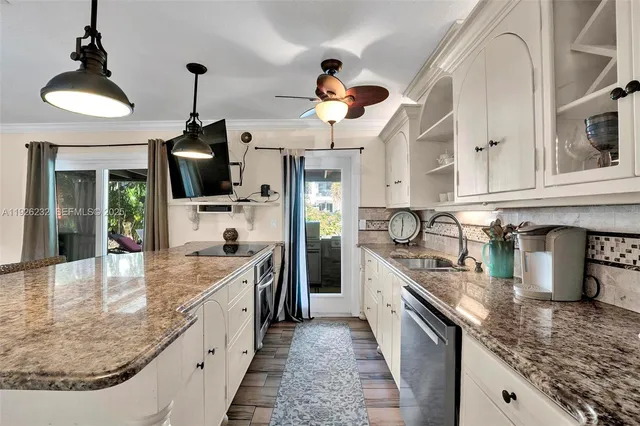a large kitchen with granite countertop a sink a counter top space appliances and cabinets