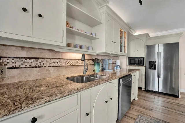 a kitchen with stainless steel appliances granite countertop a sink a stove and refrigerator